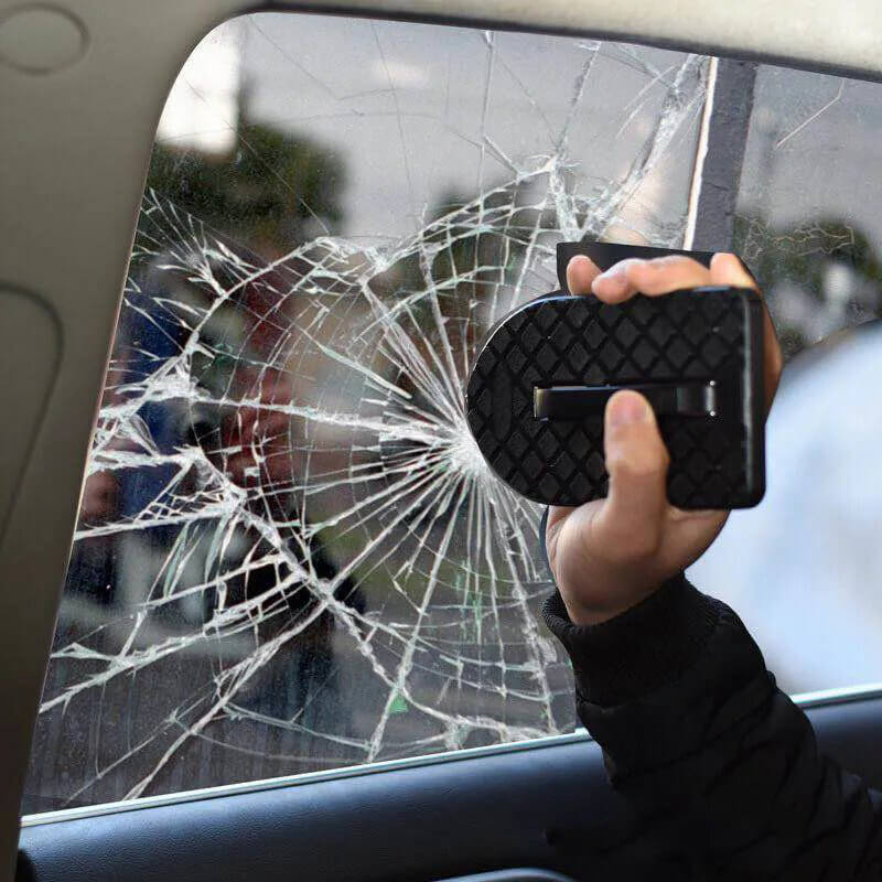Person holding a car window breaker tool in front of a shattered car window